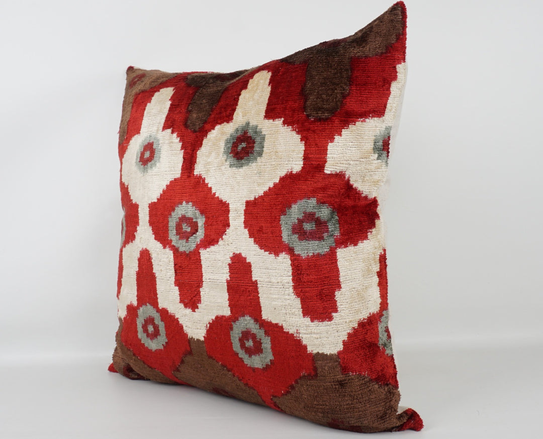 Seidenkissen 50×50 mit Ikat-Rosetten in Rot und Offwhite, Akzenten in Nougat und Grau; Vorderseite 100 % Seide (Silk-Velvet), Rückseite Baumwolle/Leinen.