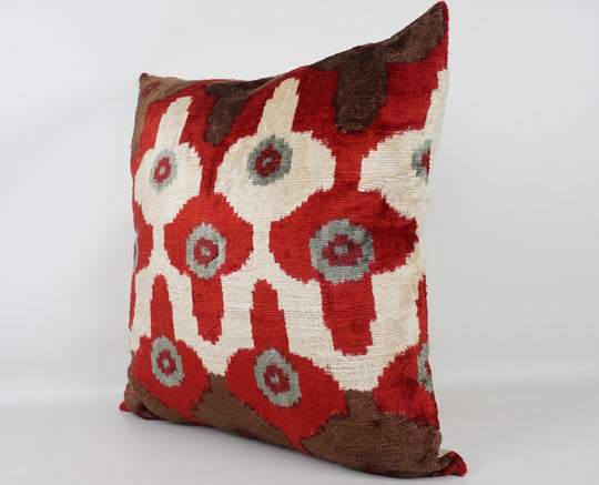 Seidenkissen 50×50 mit Ikat-Rosetten in Rot und Offwhite, Akzenten in Nougat und Grau; Vorderseite 100 % Seide (Silk-Velvet), Rückseite Baumwolle/Leinen.