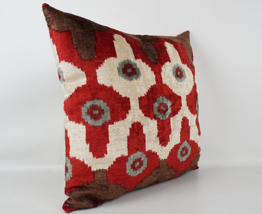 Seidenkissen 50×50 mit Ikat-Rosetten in Rot und Offwhite, Akzenten in Nougat und Grau; Vorderseite 100 % Seide (Silk-Velvet), Rückseite Baumwolle/Leinen.