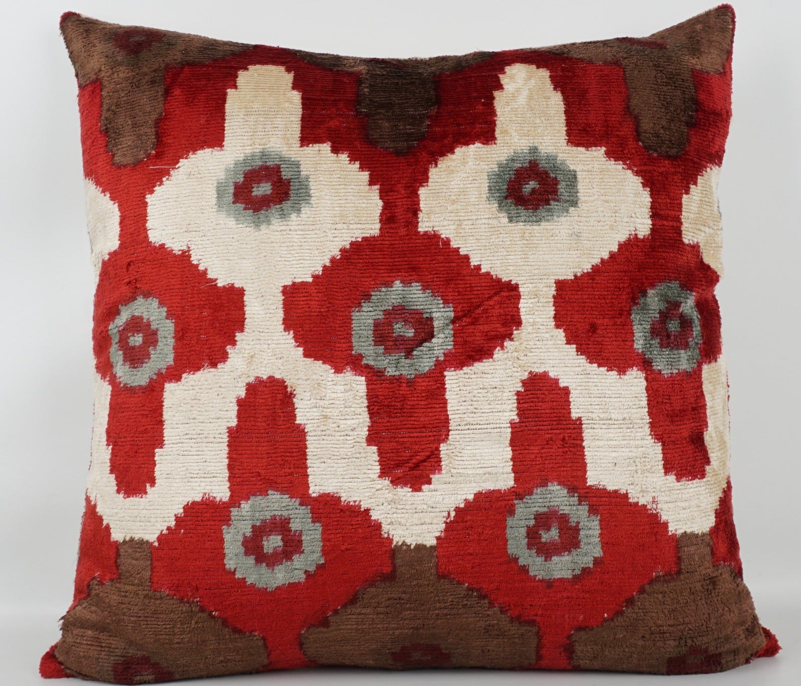 Seidenkissen 50×50 mit Ikat-Rosetten in Rot und Offwhite, Akzenten in Nougat und Grau; Vorderseite 100 % Seide (Silk-Velvet), Rückseite Baumwolle/Leinen.